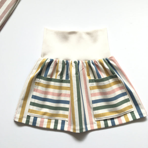 Off-white kinderrokje met strepen en steekzakken. Maat 80