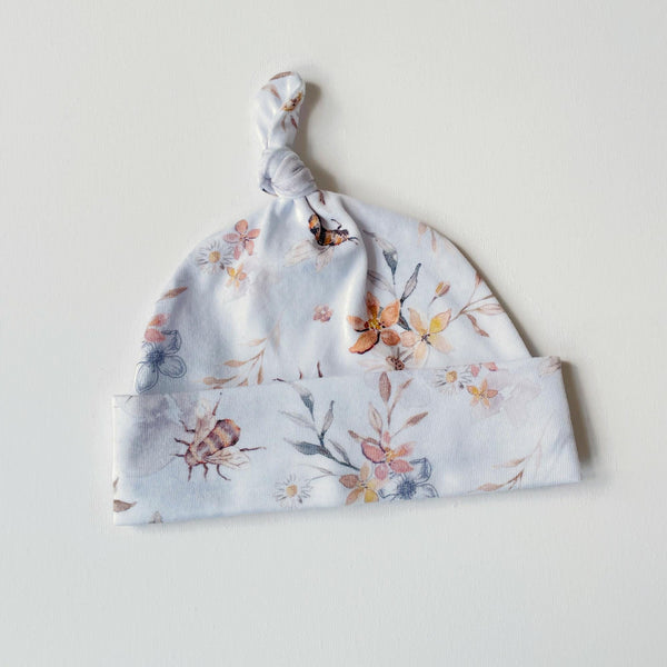 Witte baby muts van tricot met bloemen en bijtjes