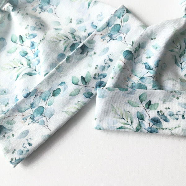 Baby muts van witte tricot met zacht groene blaadjes