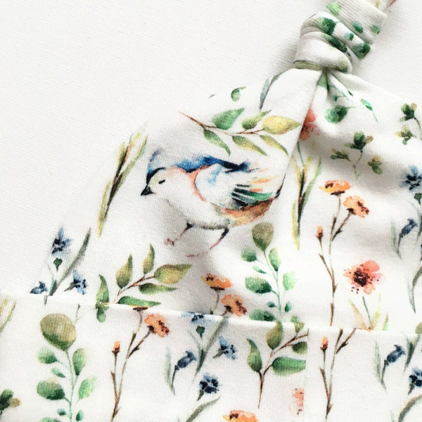 Baby muts van witte tricot met bloemetjes en vogels