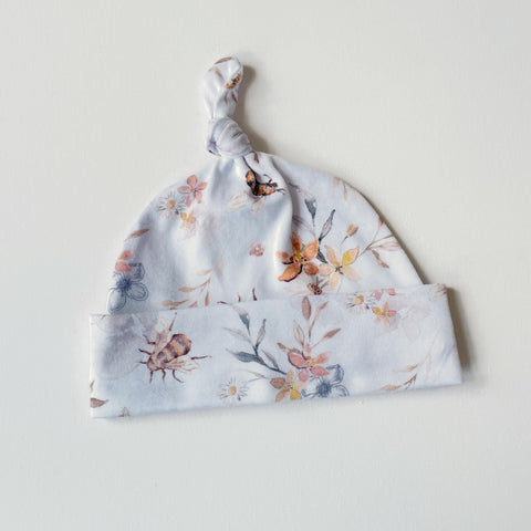 Witte baby muts van tricot met bloemen en bijtjes